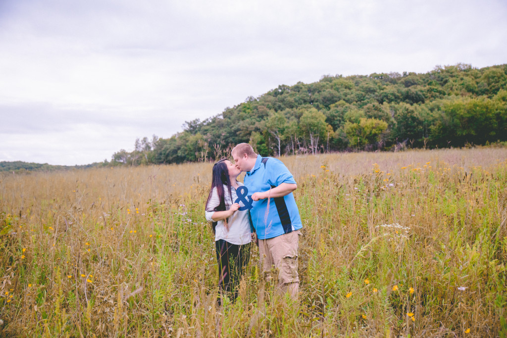 couple posing together with an ampersand sign in a beautiful Wisconsin field 
