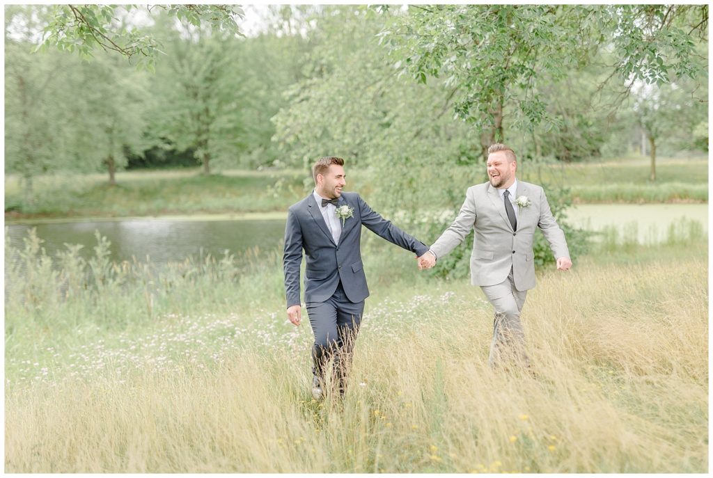 Metropolis Wisconsin Wedding wisconsin lgbt+ wedding  grooms holding hands in a field
