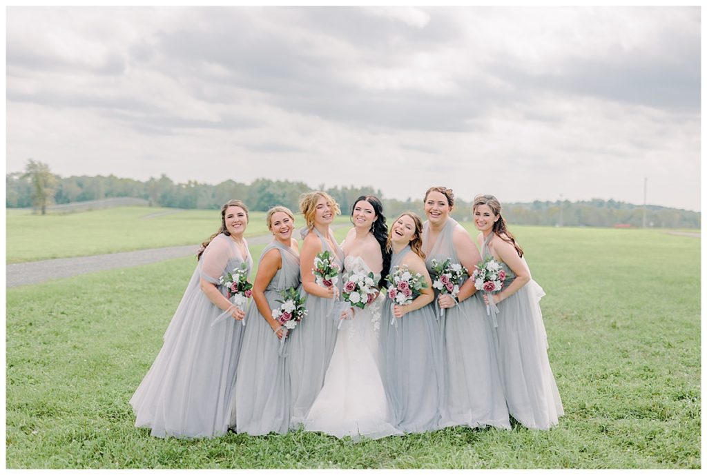 Wedding at Fest Valley Events has a rock theme including a rock tail hour. Eau Claire Wedding Photographer Alisha Marie shoots wedding outside Cadott First look at the ceremony site before wedding day photography wedding party laughing portraits