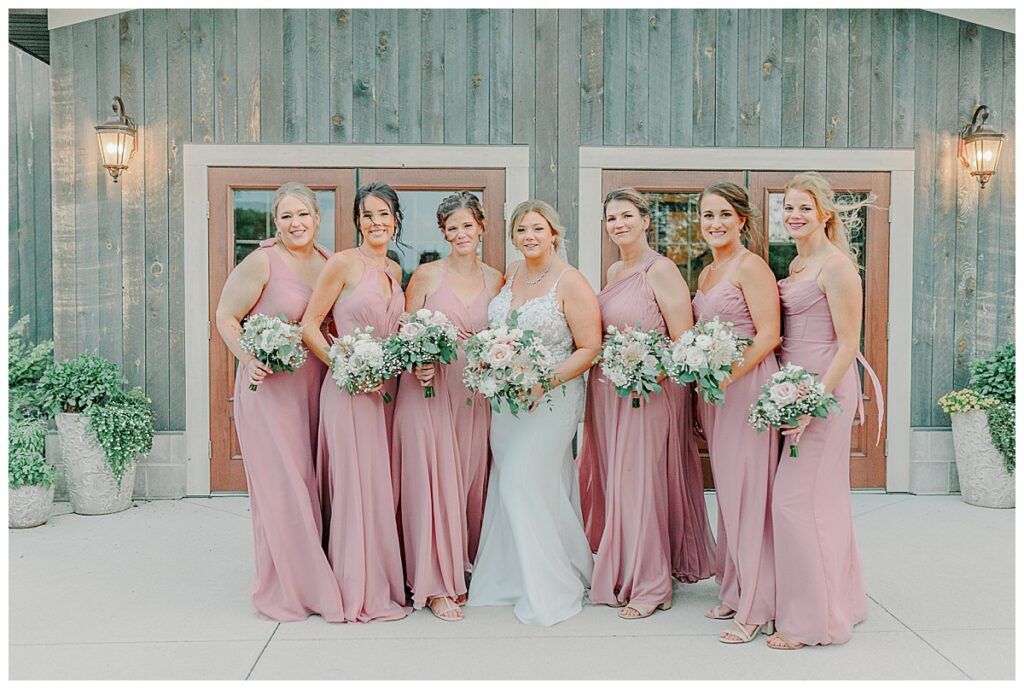 bridemaids posing for wedding portraits outside the front door of lillydale dance hall in Chippewa falls Wisconsin