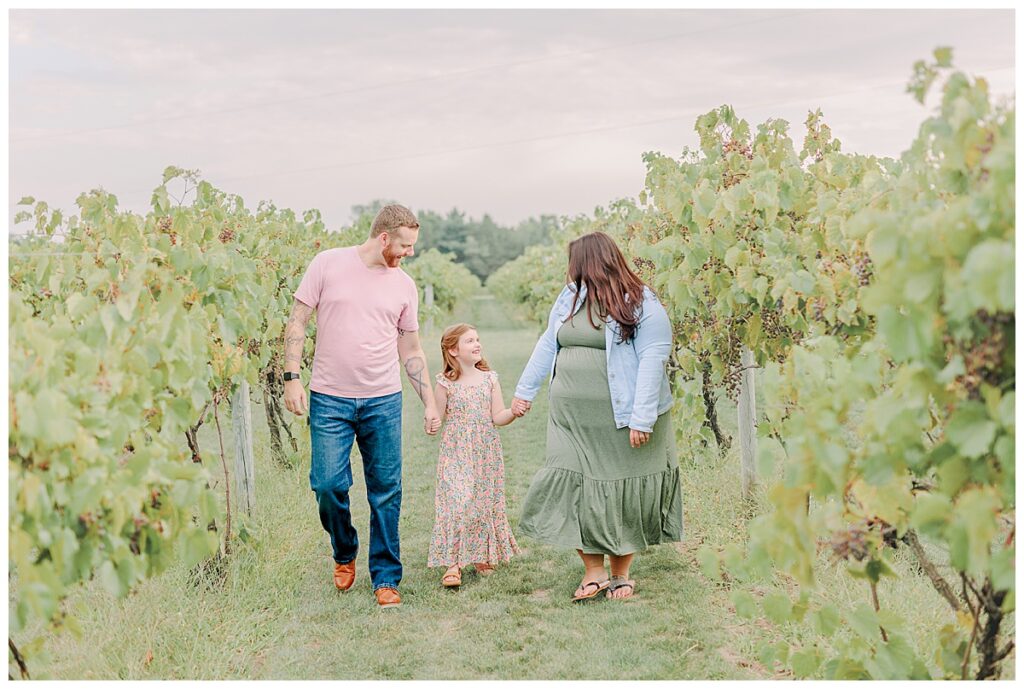 Mom and dad hold hands with their daughter for a family photography session at Riverbend Winery near Eau Claire Wisconsin Photo take by Alisha Marie Photography, Eau Claire Family Photographers; Family Photos Eau Claire