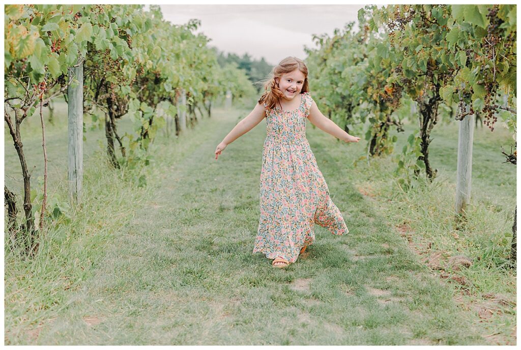 Girl twirling among the grape vines during a family photography session at Riverbend Winery Chippewa Falls Wisconsin Photo take by Alisha Marie Photography, Eau Claire Family Photographers; Family Photos Eau Claire