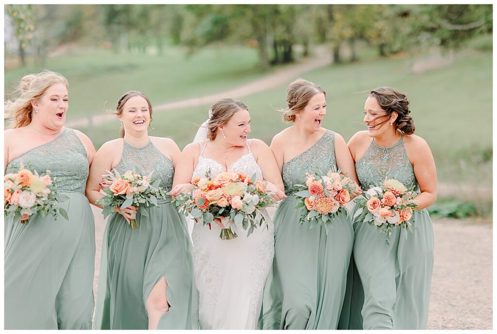 Wedding day wedding party portrait.Bridesmaids are laughing together. The women and bridesmaids wear a light green. Image by Alisha Marie Photography at the wedding venue alluring acres not far from Minneapolis, Minnesota and St. Paul