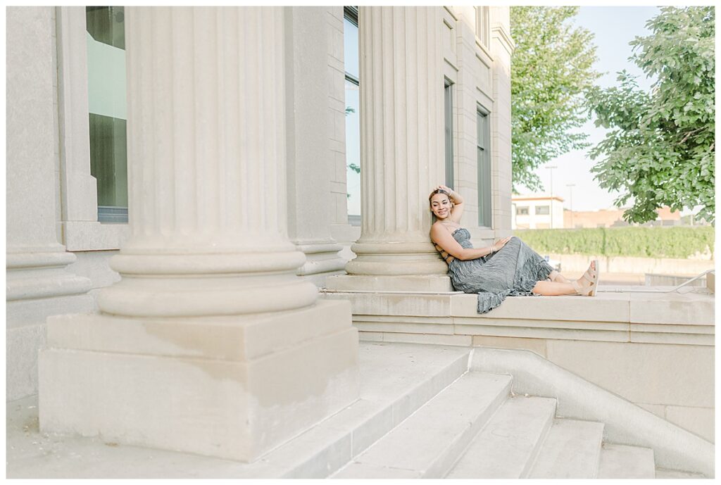 Downtown Eau Claire Senior Portraits taken at Eau Claire City Hall Old Eau Claire Library Senior Photo Session Wisconsin senior wears a light green and grey dress and 